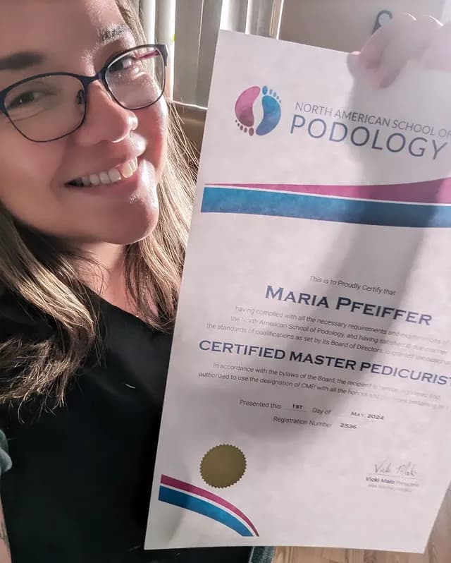 Maria Pfeiffer holding her Certified Master Pedicurist certificate
